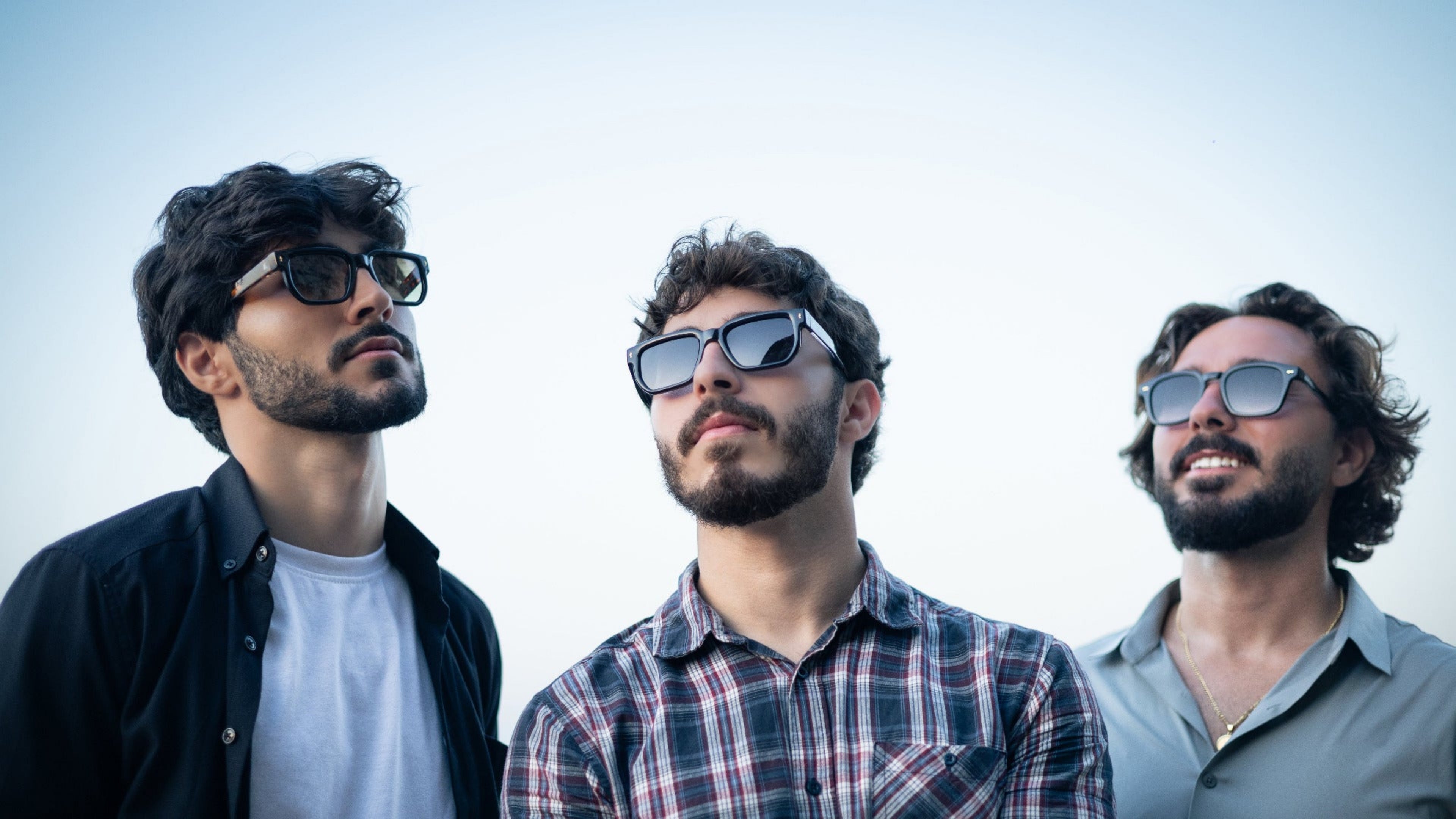 Three men wearing sunglasses against a clear sky
